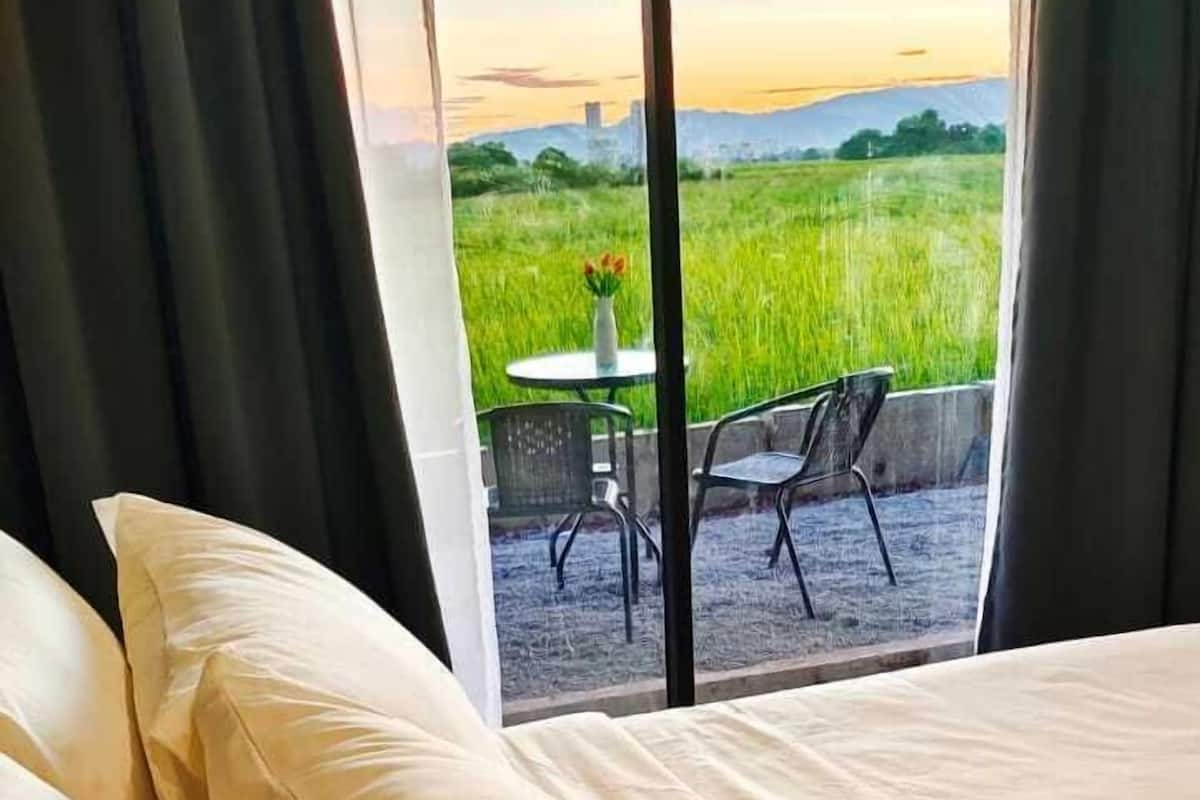 Un lit avec une literie blanche et une vue sur un patio agrémenté d’une table et de chaises.