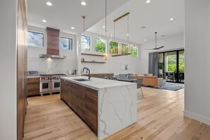 A modern kitchen with a marble island, wooden cabinets, and a built-in oven.