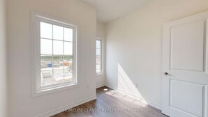 A room with a large window, a door, and a view of an industrial area. - Your vacation home @Bradford, ON (Bradford West Gwillimbury)