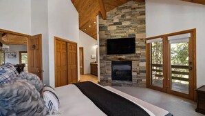 Un dormitorio con chimenea de piedra, vigas de madera en el techo y una cama grande.