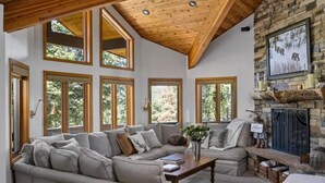 Un salón amplio con techo alto, ventanas grandes y chimenea de piedra.