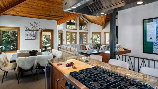Una cocina moderna con una estufa grande, techo de madera y ventanas amplias.
