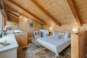 A cozy wooden cabin with a large bed, a small desk, and a bathroom. - Alpine Escape Monthly Rental (Stateline)