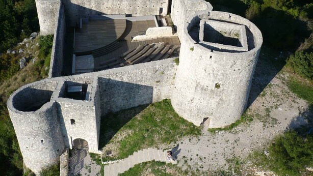 An aerial view of a historic stone fortress with a central courtyard, surrounded by walls and towers.