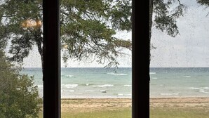 A view through a window of a beach with waves and a grassy area.