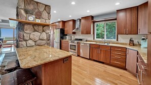 A modern kitchen with wooden cabinets, granite countertops, and a stone accent wall.
