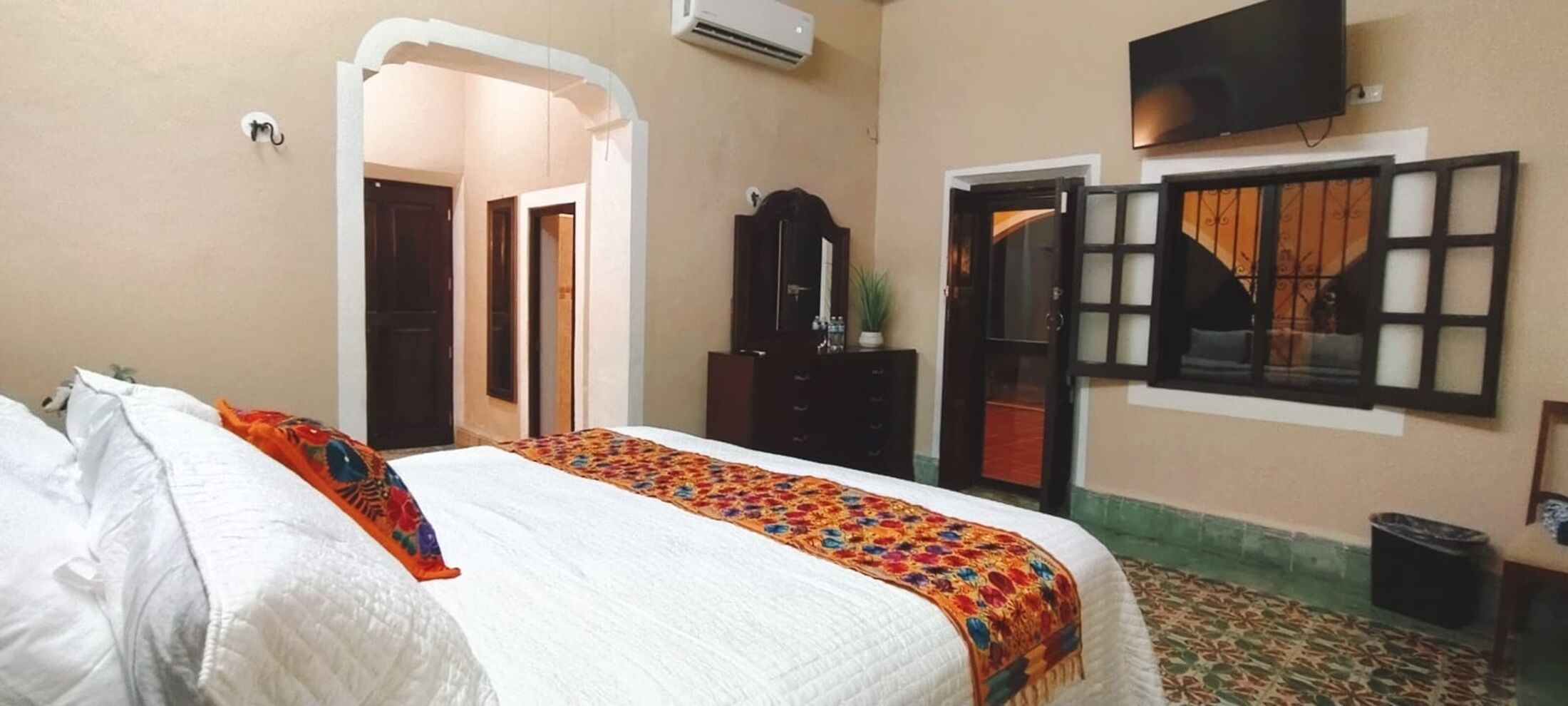 A hotel room with a bed, a wardrobe, a television, and a door.