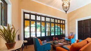 A spacious living room with a large window, a potted plant, and two sofas. - Espectacular casona con alberca y jardines (Mérida)