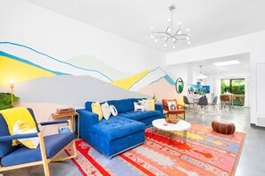 Uma sala de estar moderna com um sofá azul, uma mesa de centro e um tapete colorido.