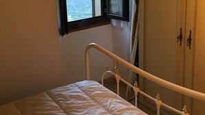 Une chambre à coucher avec un lit, une fenêtre avec des rideaux et une armoire.