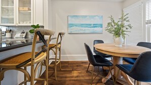 Un comedor con una mesa redonda de madera, sillas tapizadas de color negro y un jarrón blanco con una planta.