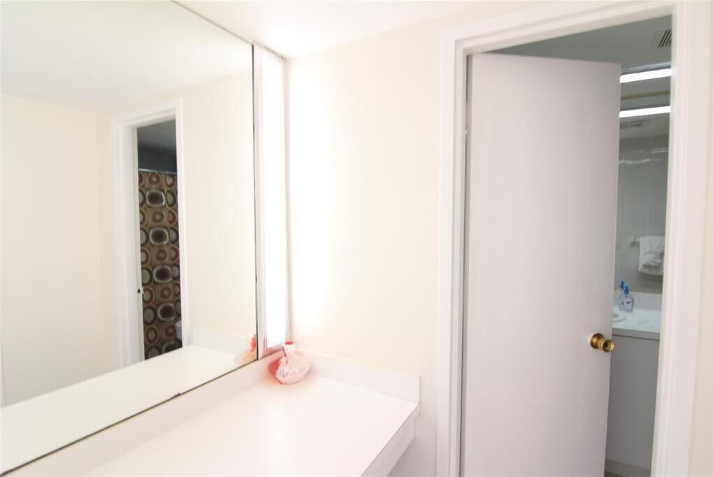 Un baño con un lavabo blanco, un espejo y una puerta que da a la zona de la ducha.
