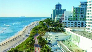 A coastal hotel with a beach view, a pedestrian walkway, and modern architecture. - Castle 1120 Cozy Studio with Intercoastal View, Free Parking, Tennis, Pool, Gym, Beach Access (Miami Beach)