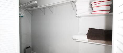Ein Badezimmer mit weiß gefliestem Boden, einer weißen Toilette, einem weißen Waschbecken und einem weißen Handtuchhalter mit Handtüchern.