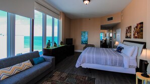 Un dormitorio con cama, sofá, escritorio y vistas al océano.