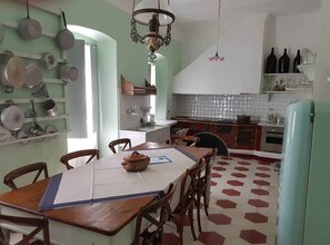 A kitchen with a dining table, chairs, and a variety of pots and pans hanging on the wall. - Holiday apartment in the medieval village of Finale Ligure (Finale Ligure)