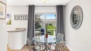 Una cocina moderna con una mesa y sillas de vidrio, una isla de cocina y vistas al exterior.