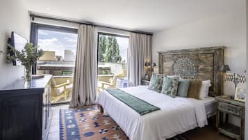 A bedroom with a large bed, a wooden headboard, a nightstand, a dresser, and a view of the outdoors.