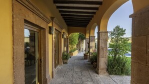 A covered outdoor corridor with stone flooring, arches, and potted plants. - Angelic Centro 2BR with Pool (San Miguel de Allende)