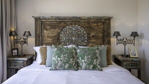 A bedroom with a large bed, two bedside tables, and a decorative headboard. - Angelic Centro 2BR with Pool (San Miguel de Allende)