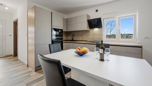 Une cuisine moderne équipée d’un four encastré, d’un four à micro-ondes et d’une grande fenêtre offrant une vue sur l’extérieur.