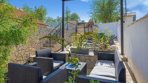 Un espace extérieur aménagé en terrasse, avec des meubles en osier et un mur en pierre.