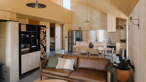 Ein modernes Interieur mit Holzboden, einem Ledersofa, einem Esstisch und einer Küchenzeile.