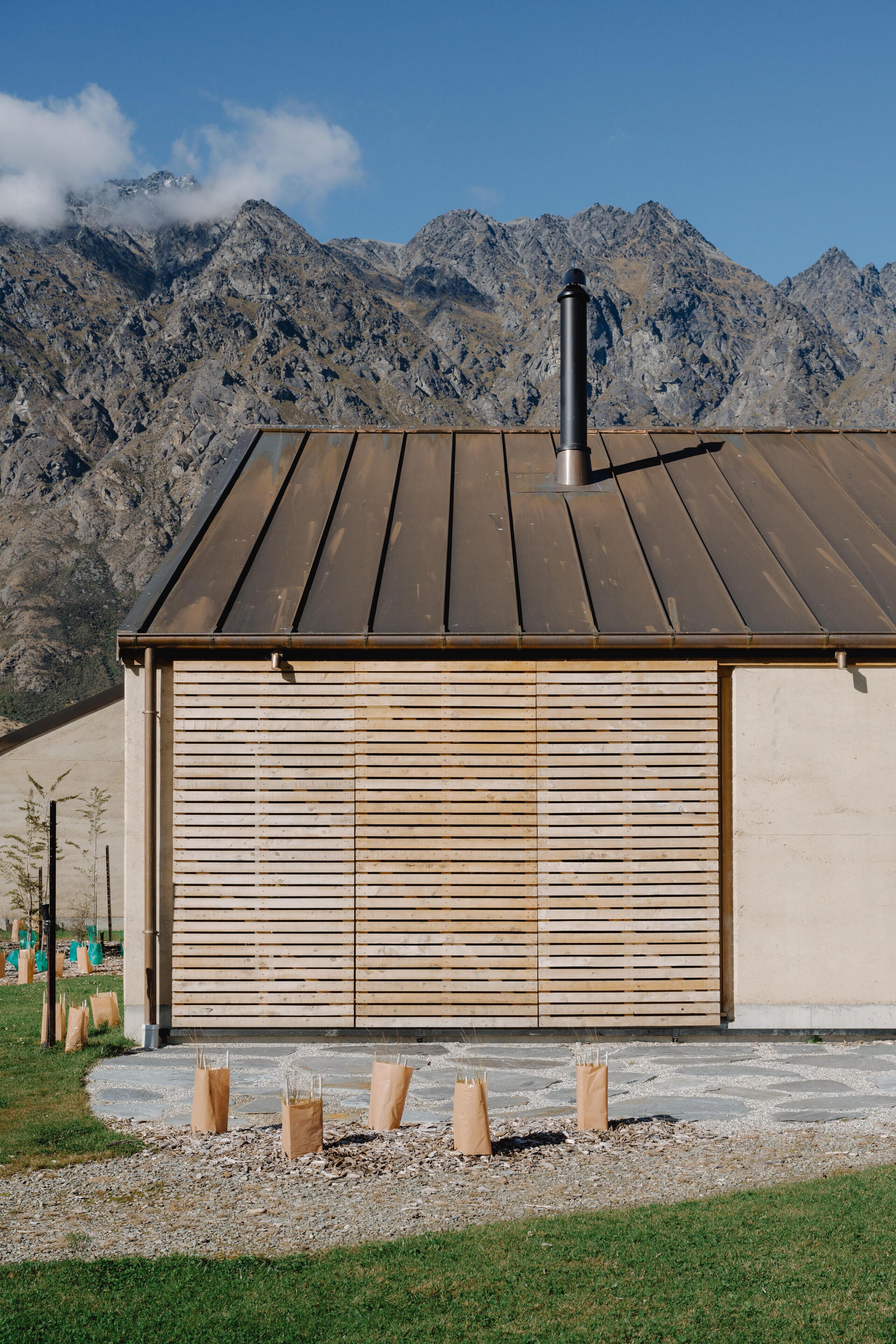 Un edificio con tetto in metallo e persiane in legno, sullo sfondo di montagne.