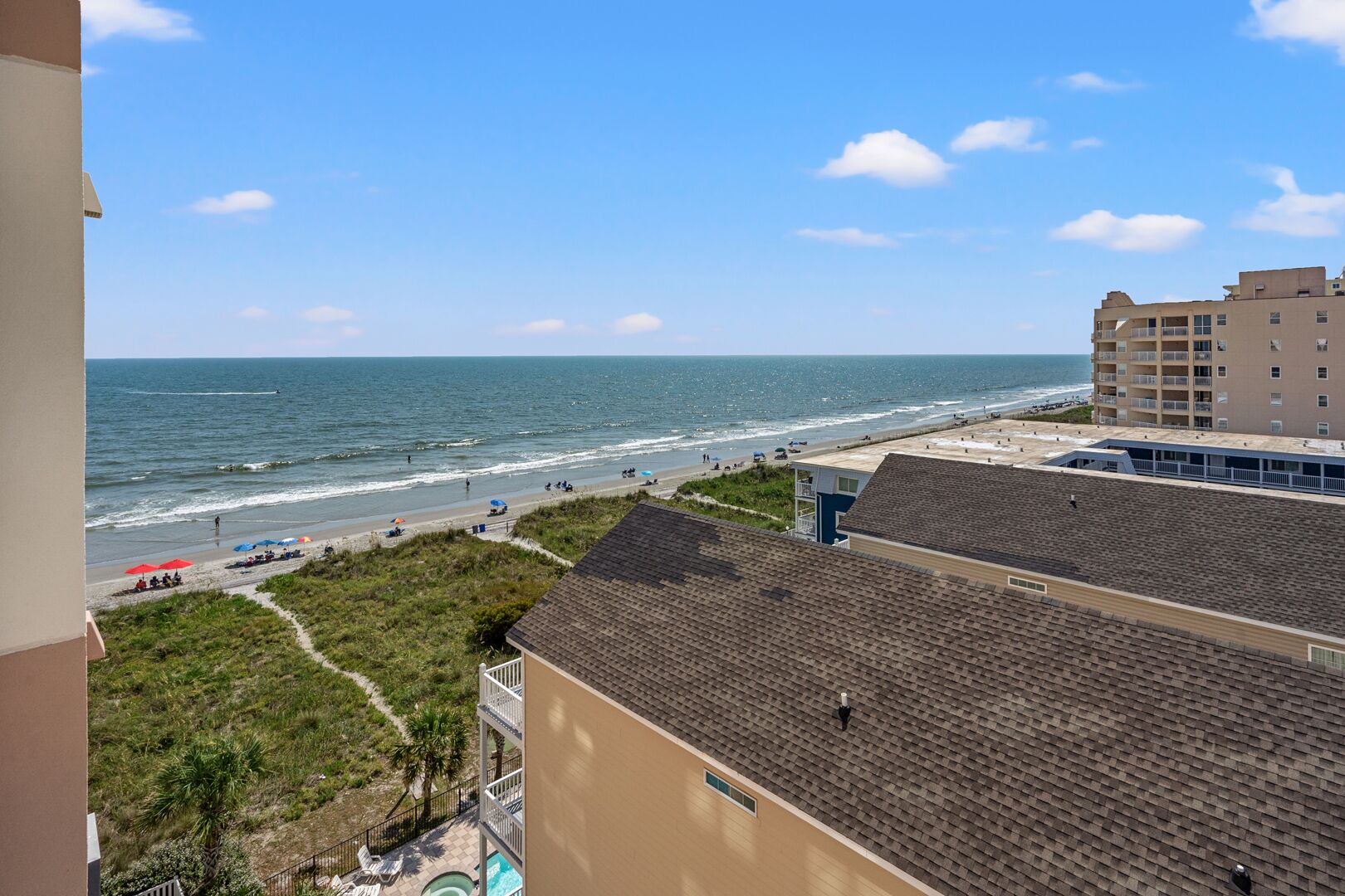 A beachfront hotel with a view of the ocean, a sandy beach, and a parking area.
