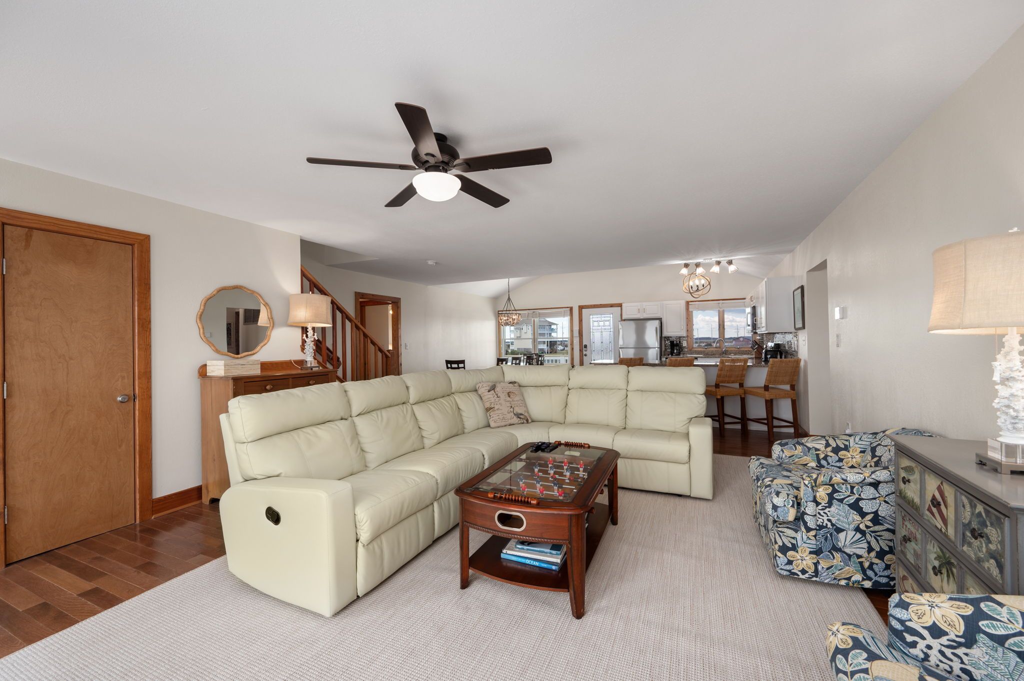 A spacious living room with a sectional sofa, a coffee table, and a dining area with a chandelier.