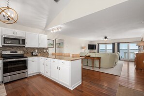 A spacious living area with a kitchen, dining space, and a balcony with a view.