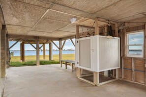 A wooden structure with a concrete floor, a bench, and a view of the water.