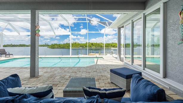 A covered outdoor area with a pool, seating, and a view of a body of water. - Heaven Found!  Stunning River Views & Pool - Villa Island Sunset - Roelens Vacations (Fort Myers)