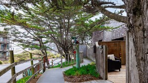 Um deck de madeira leva a um edifício com varanda e uma cadeira.