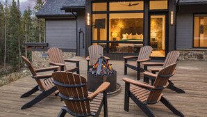 Eine Terrasse mit vier Adirondack-Stühlen und einem Feuerkorb in der Mitte.