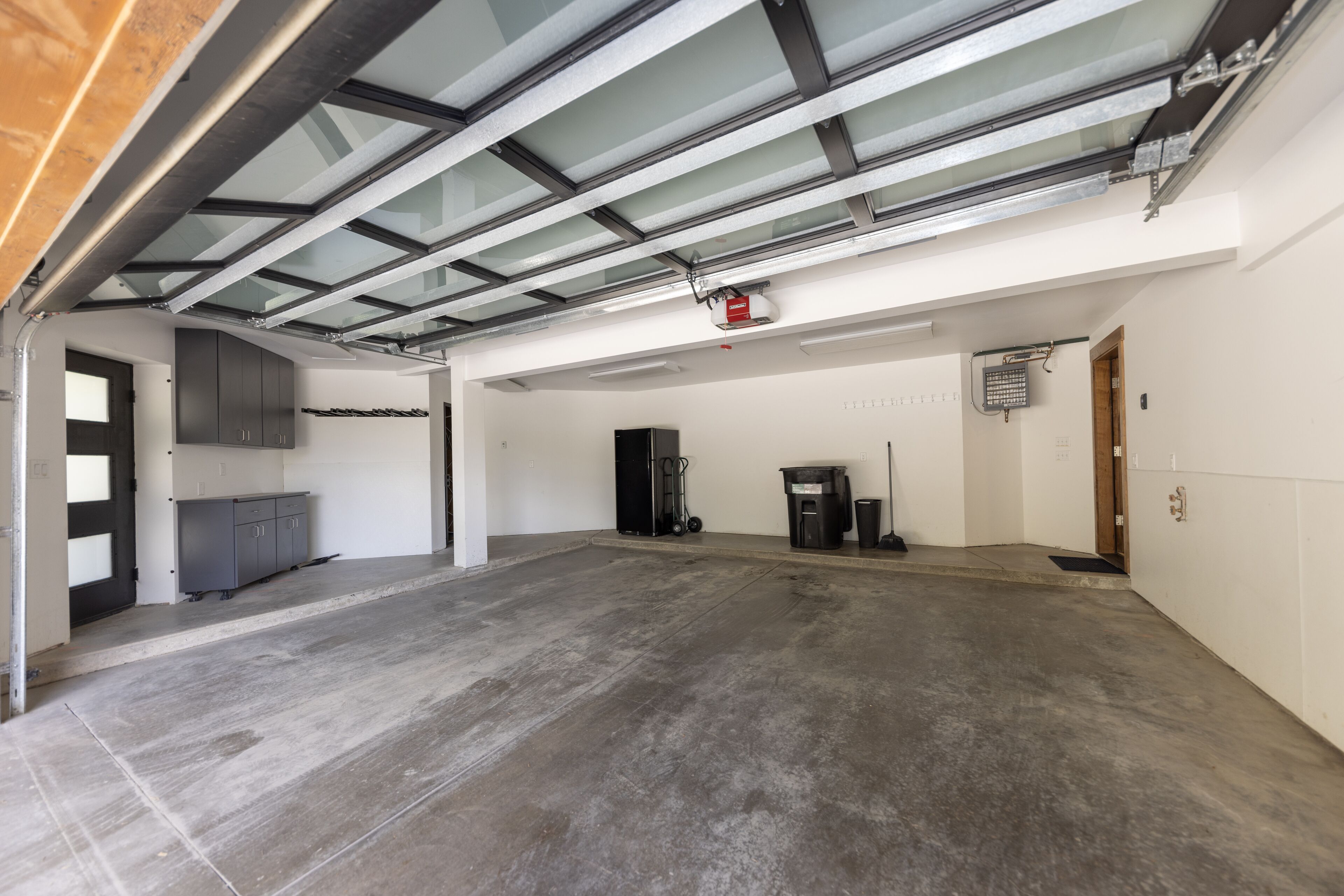 A spacious garage with a concrete floor, a skylight, and a black heater.