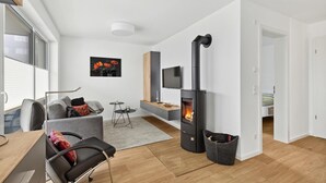 Ein modernes Wohnzimmer mit Kamin, einer Couch, einem Couchtisch und einem Fernseher.