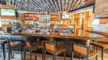 A bar area with a wooden ceiling, bar stools, and a counter.