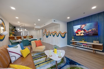 (1st Floor) Colorful open concept living room featuring multiple seating, smart TV, and designer decor.