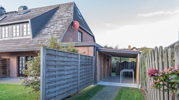 A modern house with a sloped roof, a covered patio, and a fenced backyard.