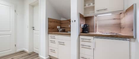 Una cocina moderna con armarios blancos, encimera de madera y cafetera integrada.