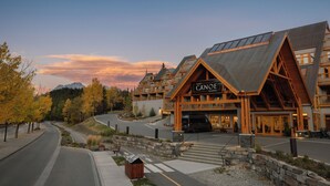 A lodge with a prominent 'Canoe & Suites' sign, a stone retaining wall, and a paved driveway leading to the entrance.