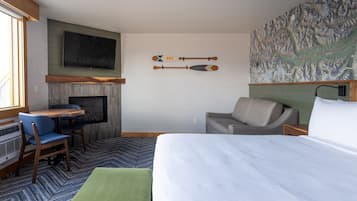 Una habitación de hotel con cama, escritorio, sillón, sofá, chimenea y un mapa mural.