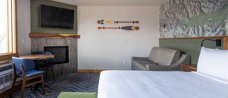 A hotel room with a bed, a desk, a chair, a sofa, a fireplace, and a wall map.