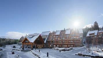 Hotelli, jossa on useita kerroksia, hiihtohissi ja lumipeitteinen maisema.