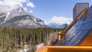 A mountain view with a modern building featuring a sloped roof and a solar panel array.