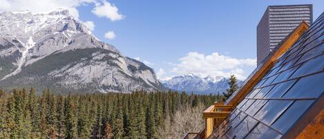 A mountain view with a modern building featuring a sloped roof and a solar panel array.