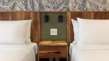 Una habitación con dos camas, un cabecero de madera, un mapa en la pared y una mesita de noche con cajón.