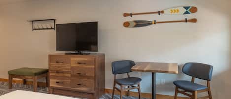 Ein Hotelzimmer mit einem Bett, einem Holzschrank, einem Fernseher, zwei Sesseln und einem Tisch.