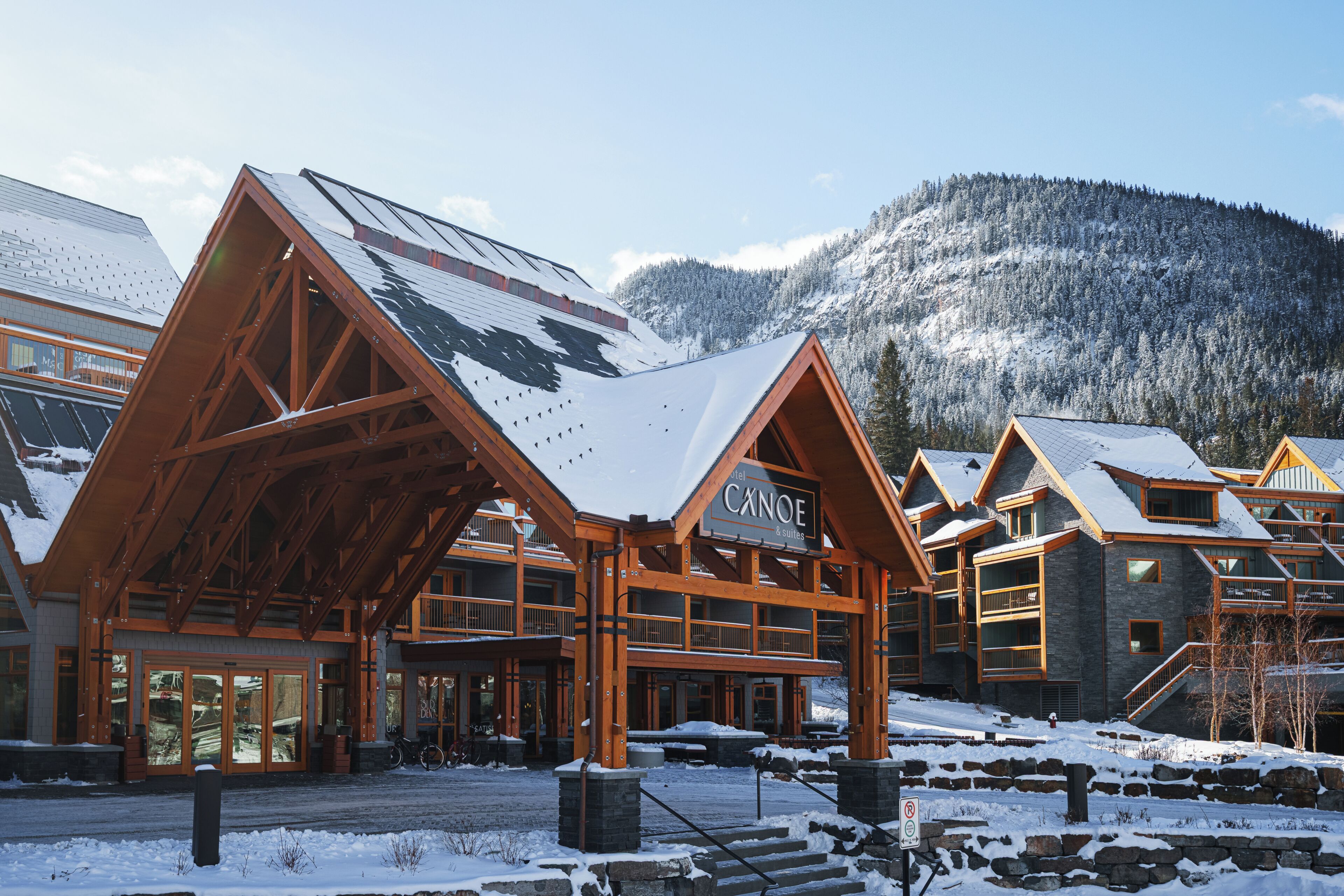 A hotel with a prominent wooden facade and a sign that reads 'CAINOE & suites.'